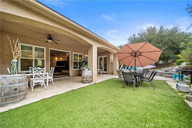 exterior space with a patio, a lawn, a ceiling fan, and stucco siding