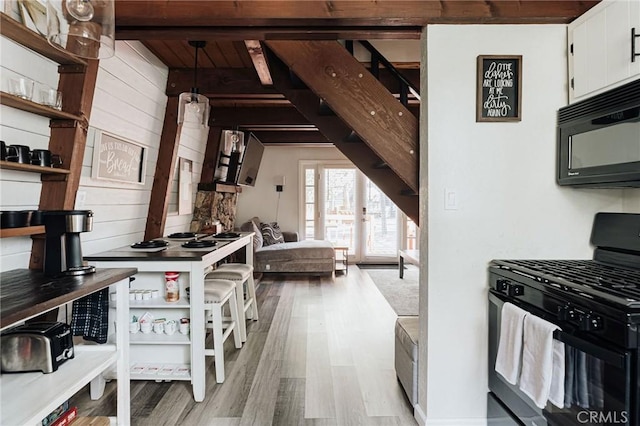 396 Kern Ave, Sugarloaf, CA 92386 - kitchen featuring white cabinetry, black appliances, wood walls, and light hardwood / wood-style flooring