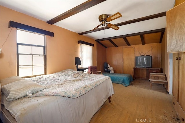 bedroom featuring multiple windows, beamed ceiling, and light wood-type flooring