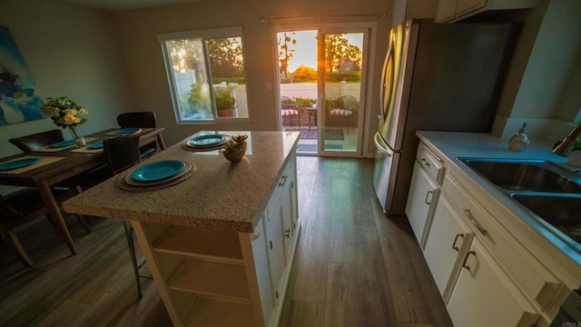 kitchen featuring sink, light hardwood / wood-style floors, white cabinetry, and stainless steel fridge