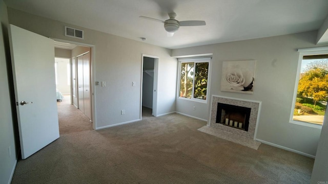 unfurnished living room featuring light carpet, a healthy amount of sunlight, ceiling fan, and a fireplace