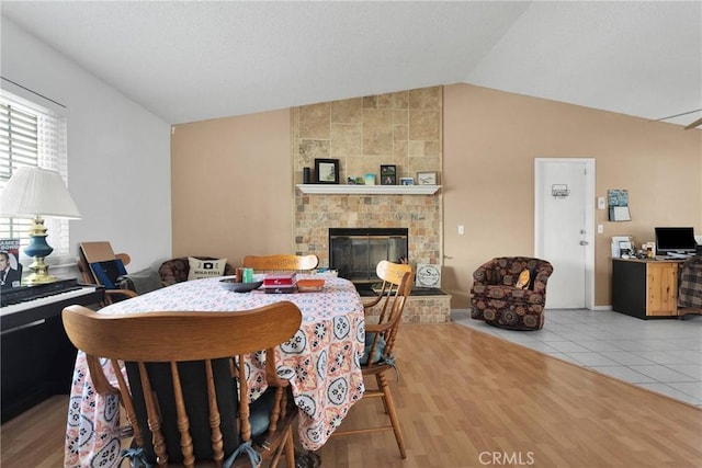 dining room with light hardwood / wood-style flooring, a large fireplace, and lofted ceiling