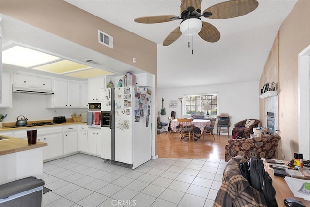 kitchen featuring light tile patterned floors, white refrigerator with ice dispenser, white cabinetry, and black gas cooktop