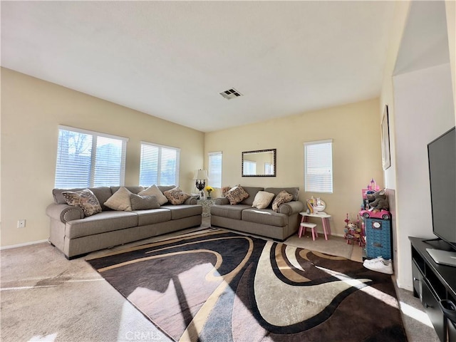 living room featuring a wealth of natural light, baseboards, visible vents, and carpet flooring