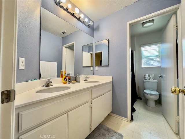 bathroom with double vanity, tile patterned flooring, toilet, and a sink