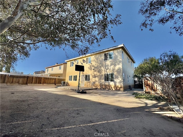 rear view of house featuring a patio area, fence, and stucco siding