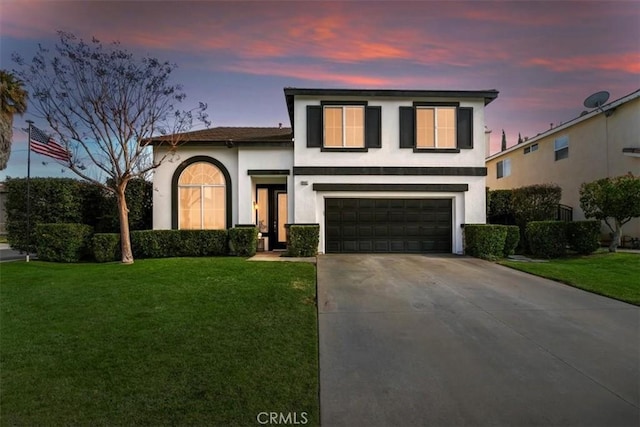 view of front of home featuring a garage, a front yard, driveway, and stucco siding