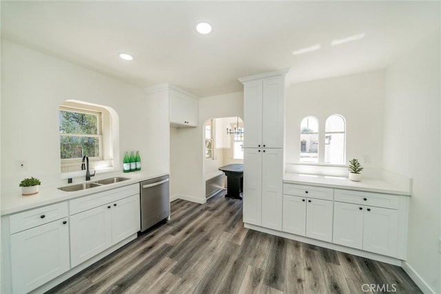 kitchen featuring dark wood finished floors, stainless steel dishwasher, white cabinets, a sink, and plenty of natural light