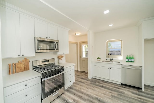 kitchen with white cabinetry, stainless steel appliances, a sink, and light countertops