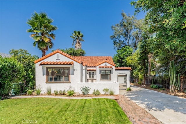 mediterranean / spanish-style home featuring stucco siding, concrete driveway, a front yard, fence, and a tiled roof