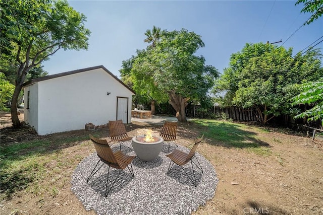 view of yard with an outbuilding, a fire pit, and fence