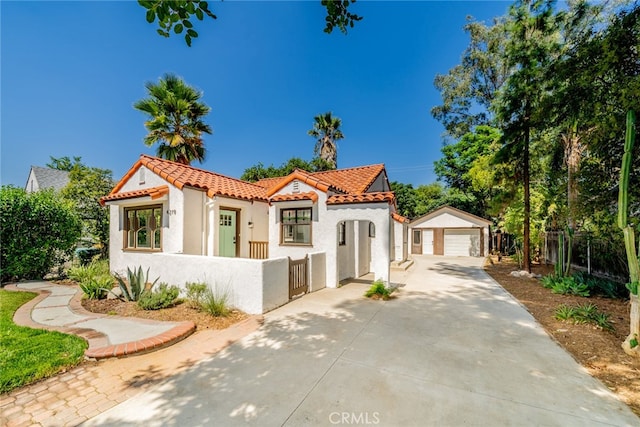 mediterranean / spanish-style house with a garage, a tiled roof, a fenced front yard, and an outdoor structure