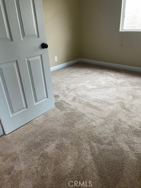 carpeted empty room with baseboards