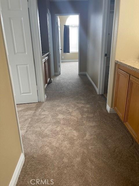 hallway featuring carpet flooring and baseboards