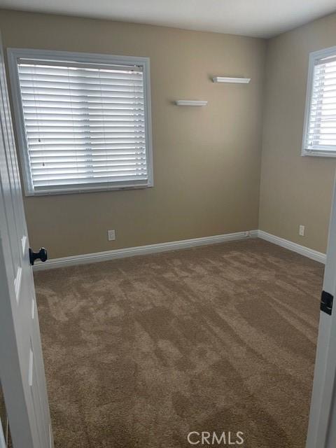 carpeted spare room featuring baseboards