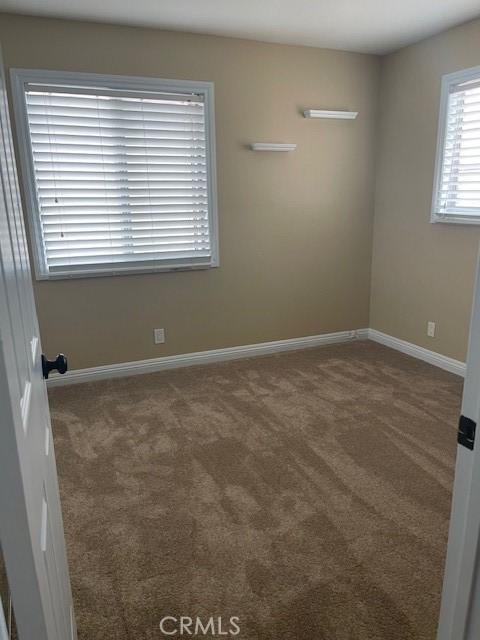 spare room featuring baseboards and carpet floors