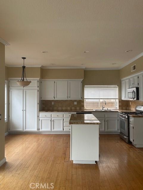 kitchen featuring a center island, visible vents, crown molding, tasteful backsplash, and appliances with stainless steel finishes