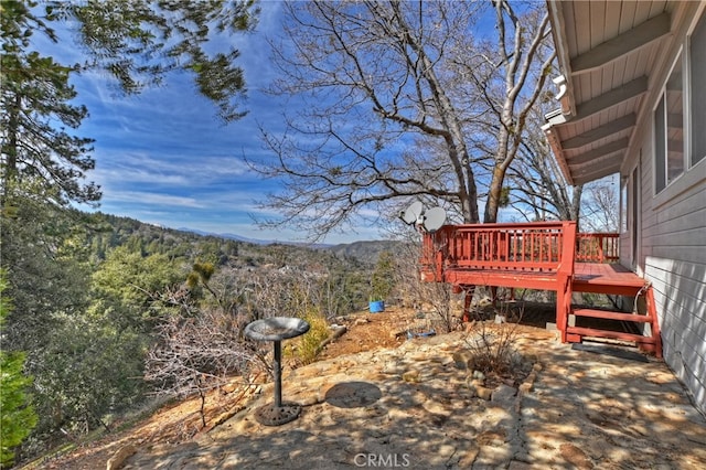 view of yard featuring a deck with mountain view and a view of trees