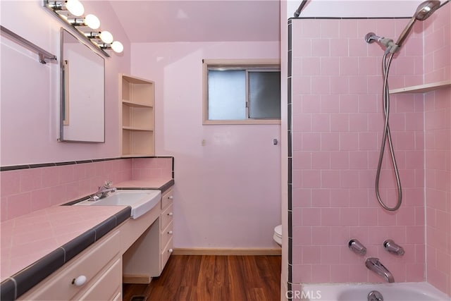 full bathroom featuring tasteful backsplash, tiled shower / bath, toilet, hardwood / wood-style floors, and vanity