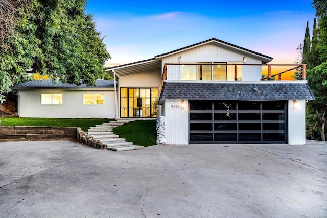 view of front facade featuring a shingled roof, concrete driveway, and a garage