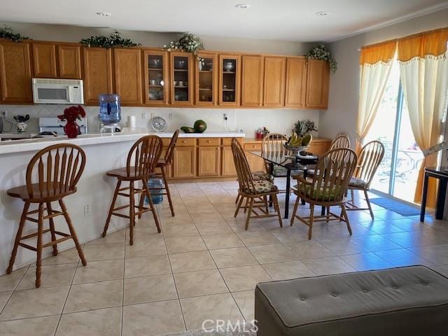 kitchen featuring range, a kitchen breakfast bar, decorative backsplash, and light tile patterned floors