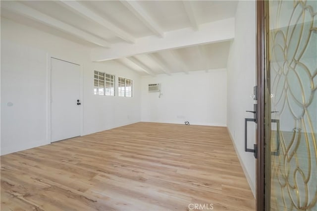 interior space featuring lofted ceiling with beams, light wood-style flooring, and a wall mounted AC