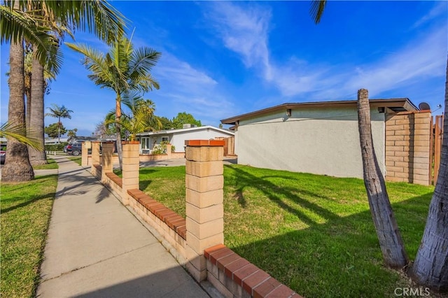 exterior space featuring a yard, fence, and stucco siding