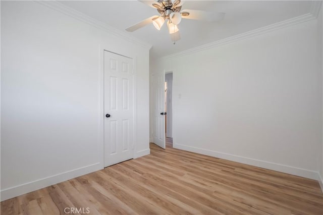 spare room with a ceiling fan, crown molding, light wood-style flooring, and baseboards