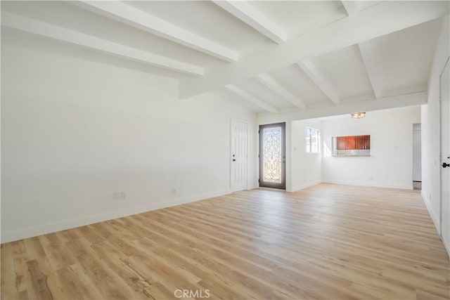 interior space featuring lofted ceiling with beams, light wood-style flooring, and baseboards