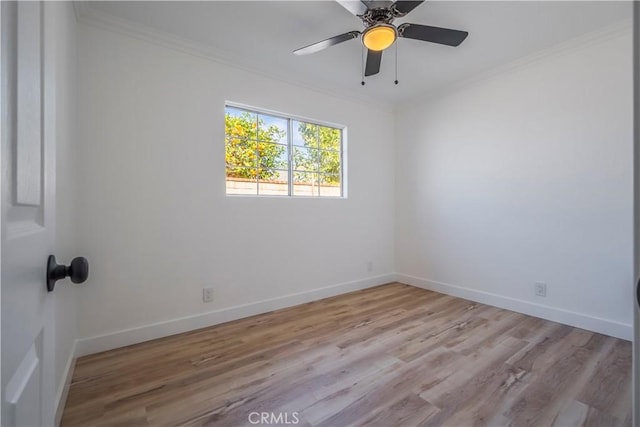 spare room with ornamental molding, light wood-style flooring, and baseboards