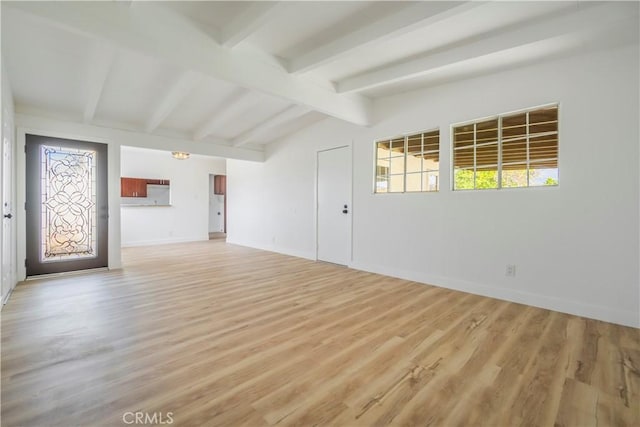 spare room with a healthy amount of sunlight, light wood-style flooring, and lofted ceiling with beams