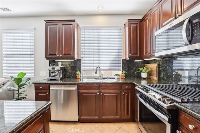 kitchen with tasteful backsplash, visible vents, appliances with stainless steel finishes, a sink, and dark stone counters