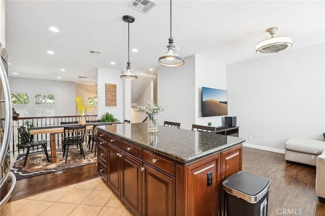 kitchen featuring visible vents, dark stone counters, open floor plan, a center island, and pendant lighting