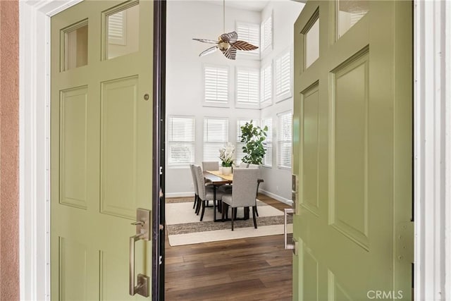 interior space featuring a towering ceiling, baseboards, and dark wood-style flooring