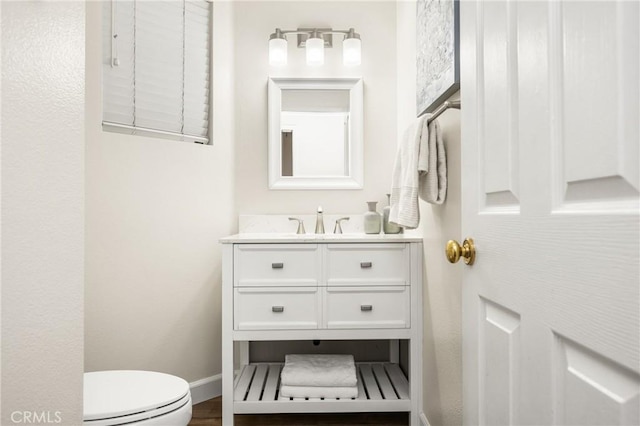 half bath with toilet, vanity, and baseboards