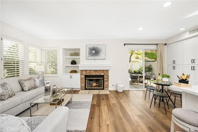 living area with visible vents, built in features, light wood-type flooring, a fireplace, and recessed lighting