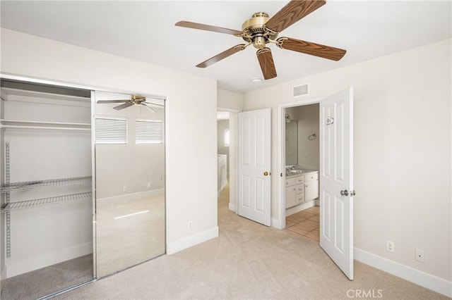 unfurnished bedroom featuring a closet, visible vents, light carpet, ceiling fan, and baseboards