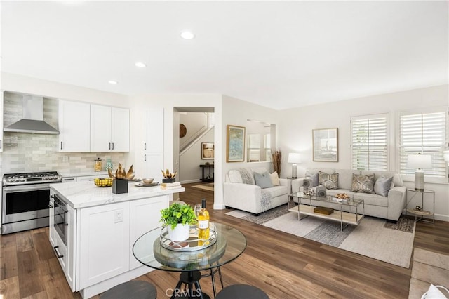 kitchen with dark wood-type flooring, a kitchen island, wall chimney range hood, stainless steel range with gas cooktop, and decorative backsplash