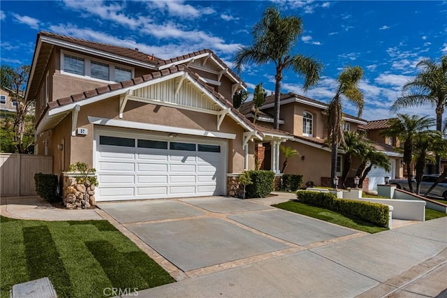 view of front facade with a garage, a tile roof, fence, concrete driveway, and stucco siding