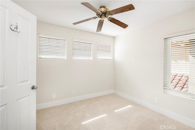 carpeted empty room featuring a ceiling fan and baseboards