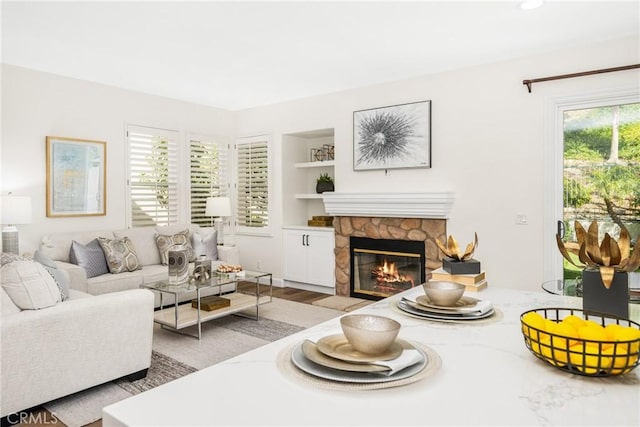 living area featuring built in shelves, a fireplace, and wood finished floors