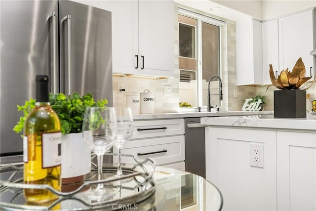 kitchen with light countertops, high end refrigerator, backsplash, and white cabinets