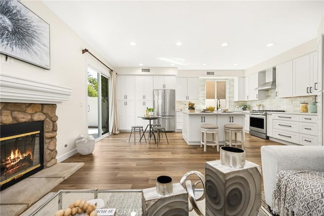 living room featuring light wood-type flooring, a fireplace, visible vents, and recessed lighting