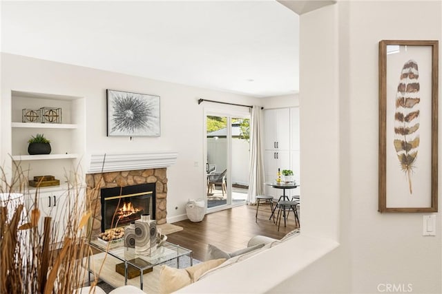 living room with baseboards, a fireplace, wood finished floors, and built in features