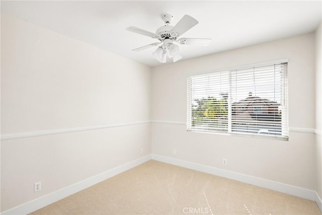 carpeted spare room with ceiling fan and baseboards