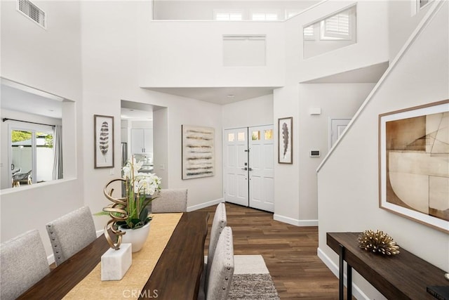 entrance foyer featuring baseboards, a high ceiling, visible vents, and dark wood-type flooring