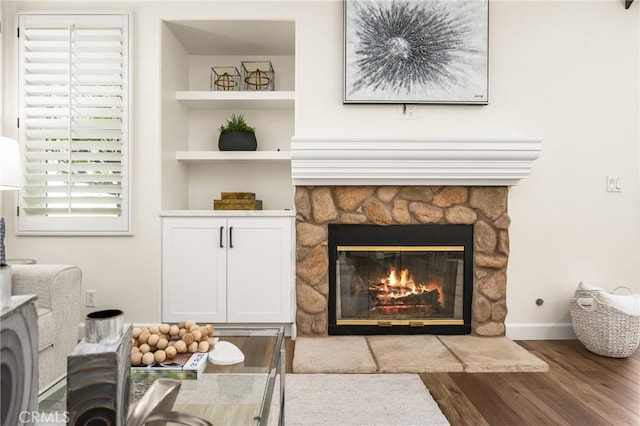 room details with built in shelves, a fireplace, baseboards, and wood finished floors