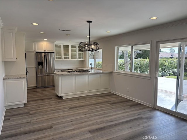 kitchen featuring stainless steel fridge, glass insert cabinets, hanging light fixtures, light stone countertops, and white cabinetry