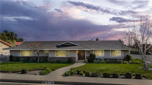 ranch-style home with a yard and fence