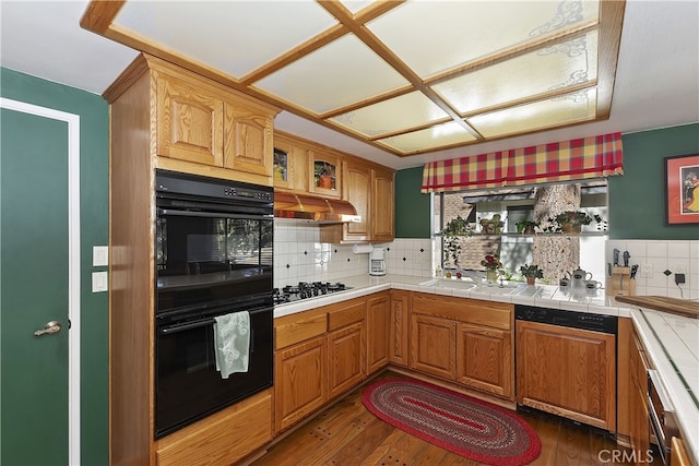 kitchen featuring paneled dishwasher, gas stovetop, dobule oven black, and tile counters